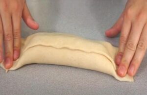 Chaparrita Step 2 Wrapping a sausage and a slice of creamy cheese in dough before sealing the ends tightly.