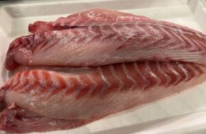 Corvina fillets Fresh, white sea bass fillets cut into thick, uniform cubes ready for the stew.