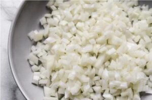 Finely diced white onions being prepared as the essential base for the traditional pino filling.