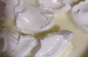 Meringue White meringue clouds floating and cooking on a surface of warm milk in a pot.