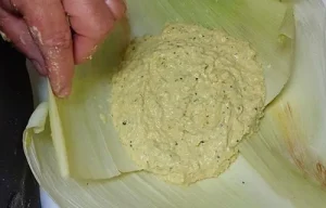 Assembly of the humitas Spreading the creamy corn and basil mixture onto overlapping corn husks to form the humita package.