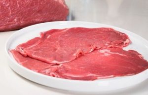 Thin slices of beef Thin, high-quality beef sirloin slices seasoned and ready for a quick sear on a hot griddle.