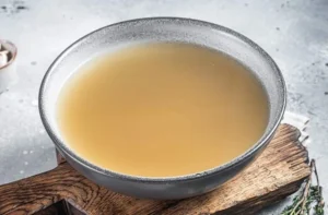 fish broth Clear, flavorful fish stock being added to the pot to deepen the soup's maritime profile.