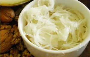 Raw alcayota pulp shredded into long, thin fibers before cooking with sugar.