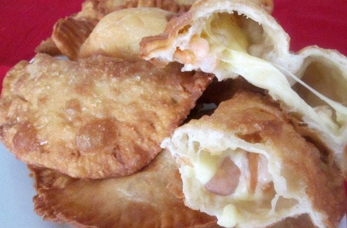 Chilean Shrimp and Cheese Empanadas — Golden Fried Empanadas de Camarón Queso Several Chilean shrimp and cheese empanadas freshly made, showing golden bubbling dough served on a rustic plate