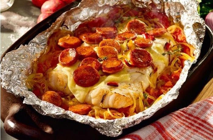 Chilean Southern Hake Cancato — baked merluza austral fillets topped with smoked longaniza, cheese, and tomato