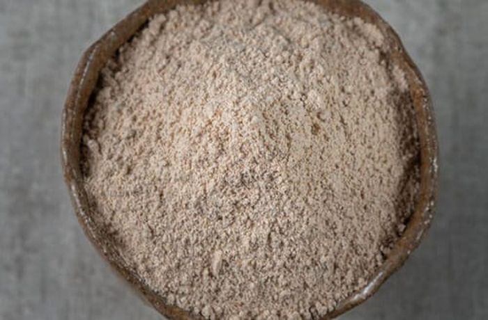Step 1 — Chilean toasted flour (harina tostada) stirred into the chicha with sugar before adding the aguardiente A rustic bowl of Chilean toasted wheat flour — light brown in color and fine in texture — ready to be stirred into chicha for the pihuelo cocktail