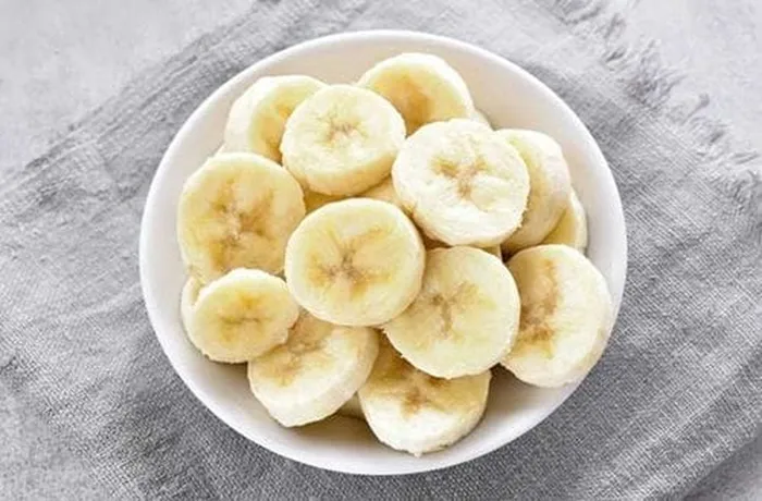 Ripe banana slices arranged on the pre-baked kuchen base before adding the pastry cream — Chilean banana kuchen filling
