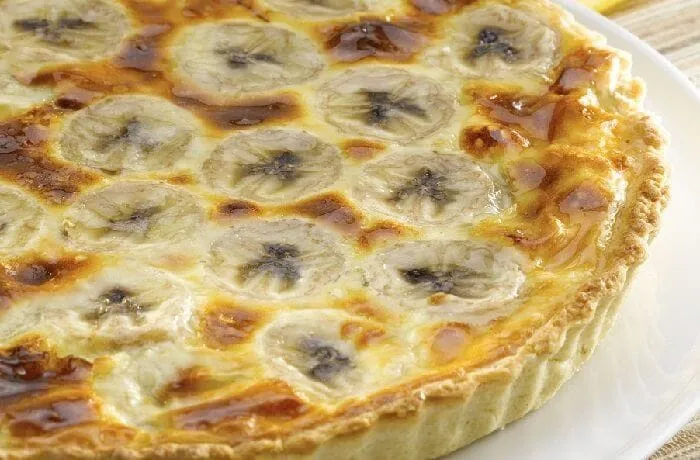 Chilean banana kuchen (kuchen de platano) — homemade tart with ripe banana slices and pastry cream on a butter shortcrust base, southern Chile style