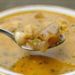 Chilean beef foot broth (caldo de pata de vacuno) served in a deep bowl with cilantro and semolina