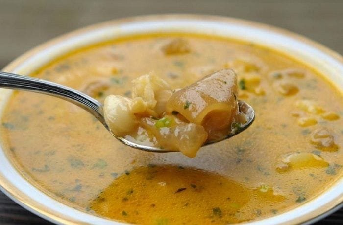 Chilean beef foot broth (caldo de pata de vacuno) served in a deep bowl with cilantro and semolina