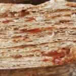 Traditional Chilean mil hojas cake decorated with manjar, crushed walnuts, and powdered sugar