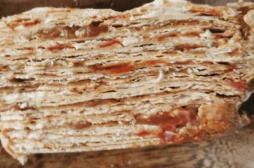 Traditional Chilean mil hojas cake decorated with manjar, crushed walnuts, and powdered sugar