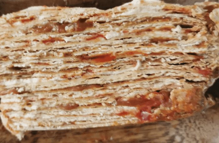 Traditional Chilean mil hojas cake decorated with manjar, crushed walnuts, and powdered sugar