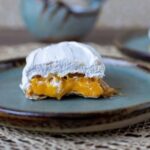 Chilean príncipes assembled with three layers of crispy hojarasca wafer, filled with bright golden huevo mol, and coated in firm white Swiss meringue.