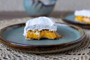 Chilean príncipes assembled with three layers of crispy hojarasca wafer, filled with bright golden huevo mol, and coated in firm white Swiss meringue.