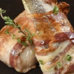 Chilean roasted hake fillets wrapped in bacon with bay leaves, butter, and lemon — traditional merluza con tocino recipe