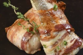 Chilean roasted hake fillets wrapped in bacon with bay leaves, butter, and lemon — traditional merluza con tocino recipe