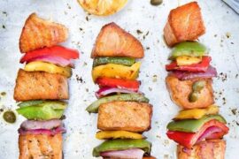 Chilean salmon skewers (brochetas de salmón) with tri-color bell peppers and red onion on a platter