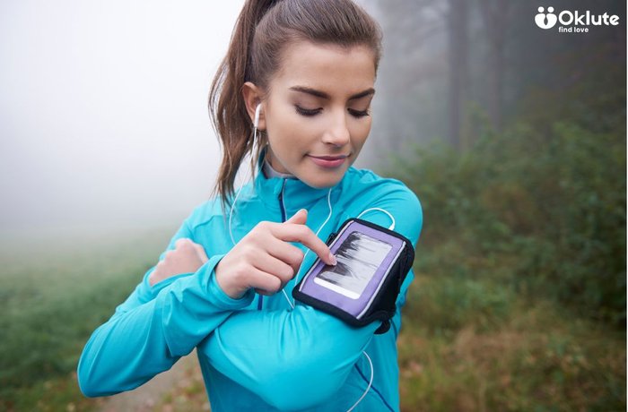Deportista con app móvil Deportista con auriculares usando aplicación móvil en ruta de running