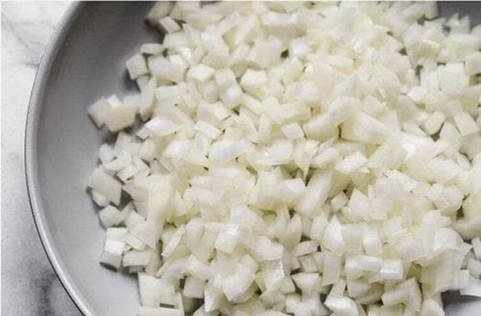 Diced onion being sautéed in oil — base sofrito for Chilean abalone empanada filling