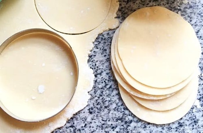 Rolled-out empanada dough circles on a floured surface, ready to be filled with the cinnamon apple mixture.