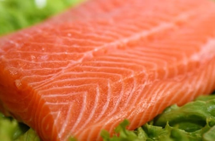 Fresh salmon fillet cut into 3 cm cubes for Chilean brochetas de salmón — seasoned with lemon, salt and pepper