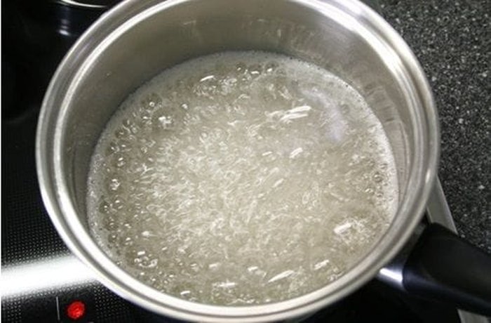 Hot liquid caramel being poured and swirled inside an individual flan mold to coat the bottom and sides before the custard is added.