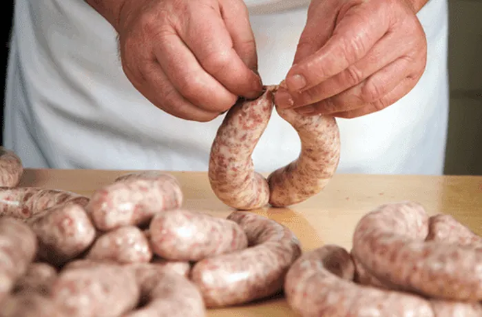 Chilean San Carlos longanizas stuffed into natural pork casing and tied into 15 cm portions — ready for the 4 to 6 hour air-drying phase