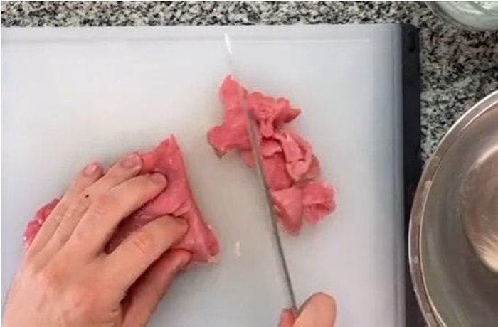 Beef cut into thin strips in a bowl, ready to be marinated with soy sauce and cornstarch