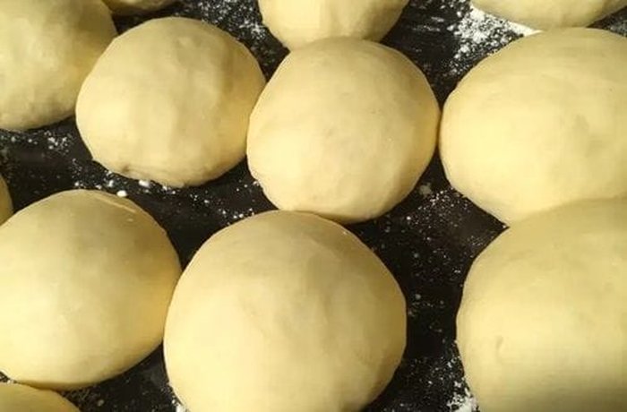 Chilean berlines dough shaped into small balls and dusted with flour, ready to fry.
