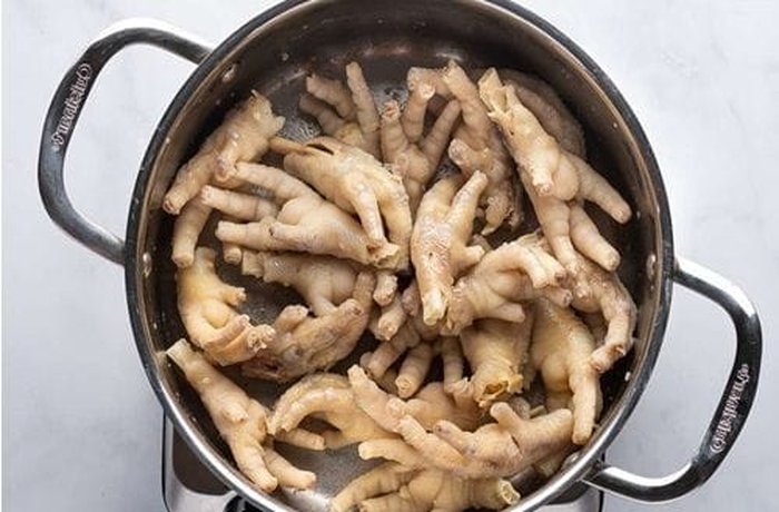 Cleaned and blanched chicken feet boiling in water, the first step for the slow collagen extraction