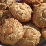Round almendrados coated in powdered sugar and topped with a whole almond, ready to bake