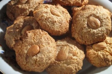 Round almendrados coated in powdered sugar and topped with a whole almond, ready to bake