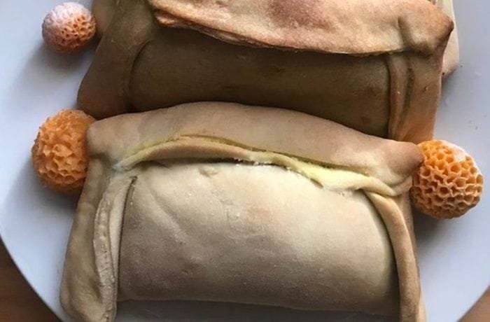 Freshly baked Chilean diguenes empanadas, golden and crisp, on a white plate