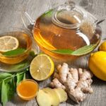 Steaming cup of bariatric tea with floating lemon slices and a cinnamon stick, beside fresh ginger and mint leaves