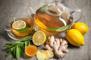 Steaming cup of bariatric tea with floating lemon slices and a cinnamon stick, beside fresh ginger and mint leaves