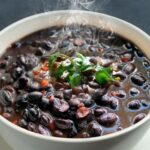 Chilean black beans with rice topped with golden longaniza slices and parsley