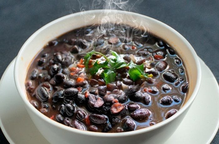 Chilean black beans with rice topped with golden longaniza slices and parsley