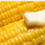 Chilean boiled corn on the cob topped with melting butter on a serving plate
