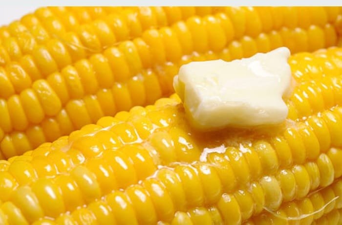 Chilean boiled corn on the cob topped with melting butter on a serving plate