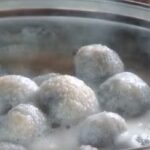 Chilean bolitas de indio, small potato dumplings served cold in sweet spiced milk in a dessert bowl