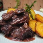 Chilean asado de tira braised in dark beer with carrots and peppers in a rustic dish