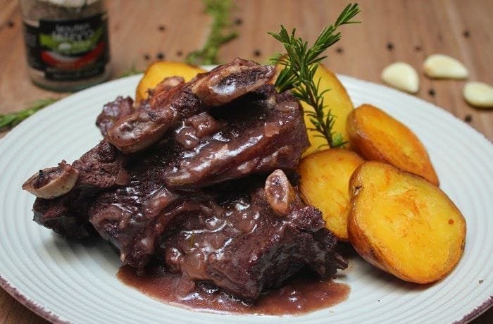 Chilean asado de tira braised in dark beer with carrots and peppers in a rustic dish