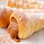 Baked Chilean cachitos filled with manjar, dusted with powdered sugar and grated coconut