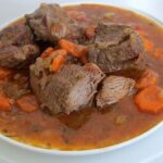 Chilean carne al jugo, tender beef pieces in a thick savory sauce served in a deep plate