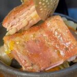 Chilean chancho borracho served in a clay pot, with smoked pork ribs, longaniza sausage, and cabbage.