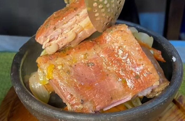 Chilean chancho borracho served in a clay pot, with smoked pork ribs, longaniza sausage, and cabbage.