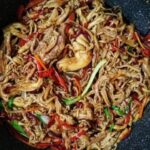 Bowl of noodles with sauteed changles coral mushrooms, bell peppers, and onion