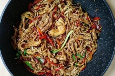Bowl of noodles with sauteed changles coral mushrooms, bell peppers, and onion